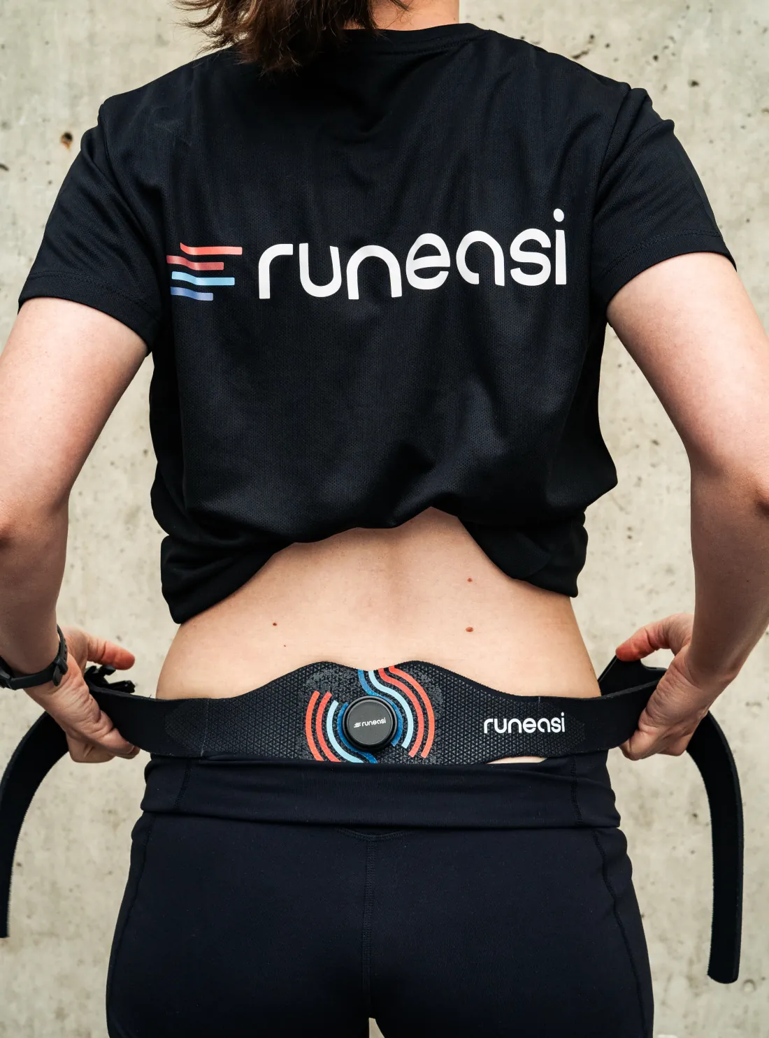 A runner lifts her shirt to show the Runeasi belt fitted around her lower back