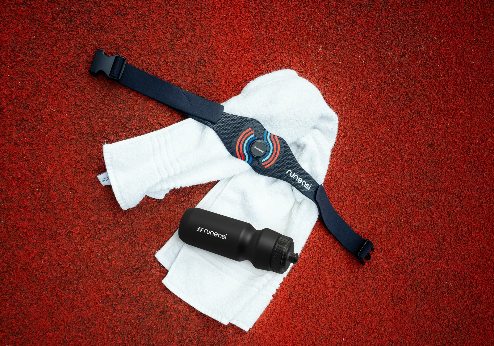 A Runeasi belt, a towel and a water bottle on a red running track