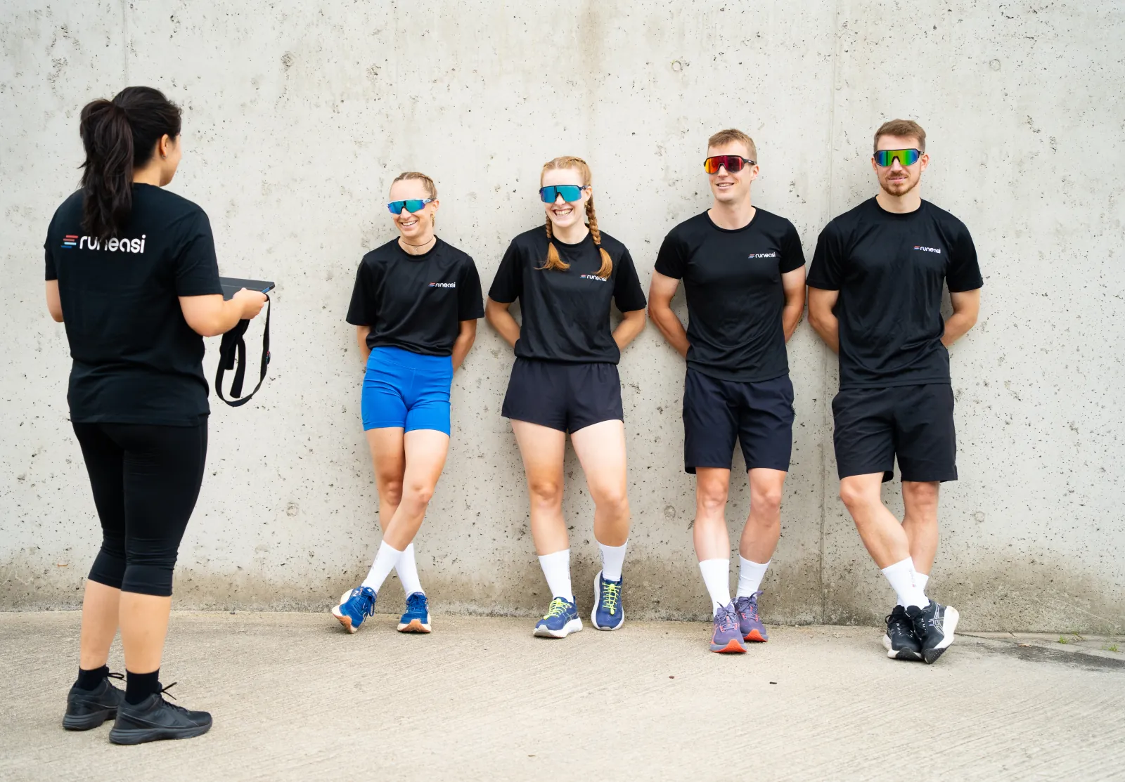 A tester holds up a Runeasi belt in front of four runners standing by a concrete wall