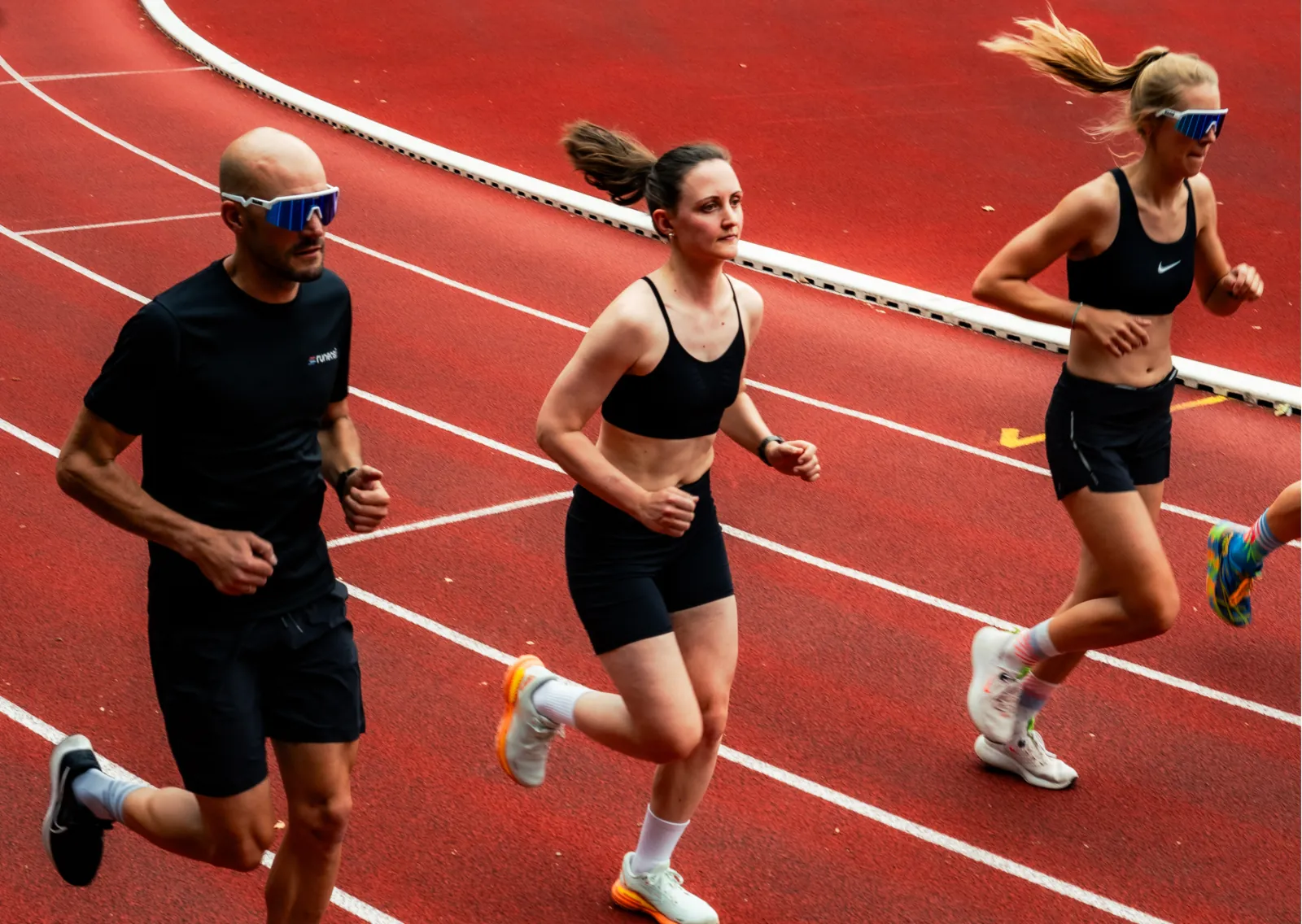 Three runners on a red running track