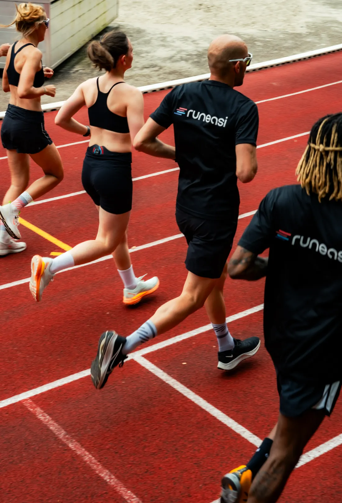 A group of runners on a red running track