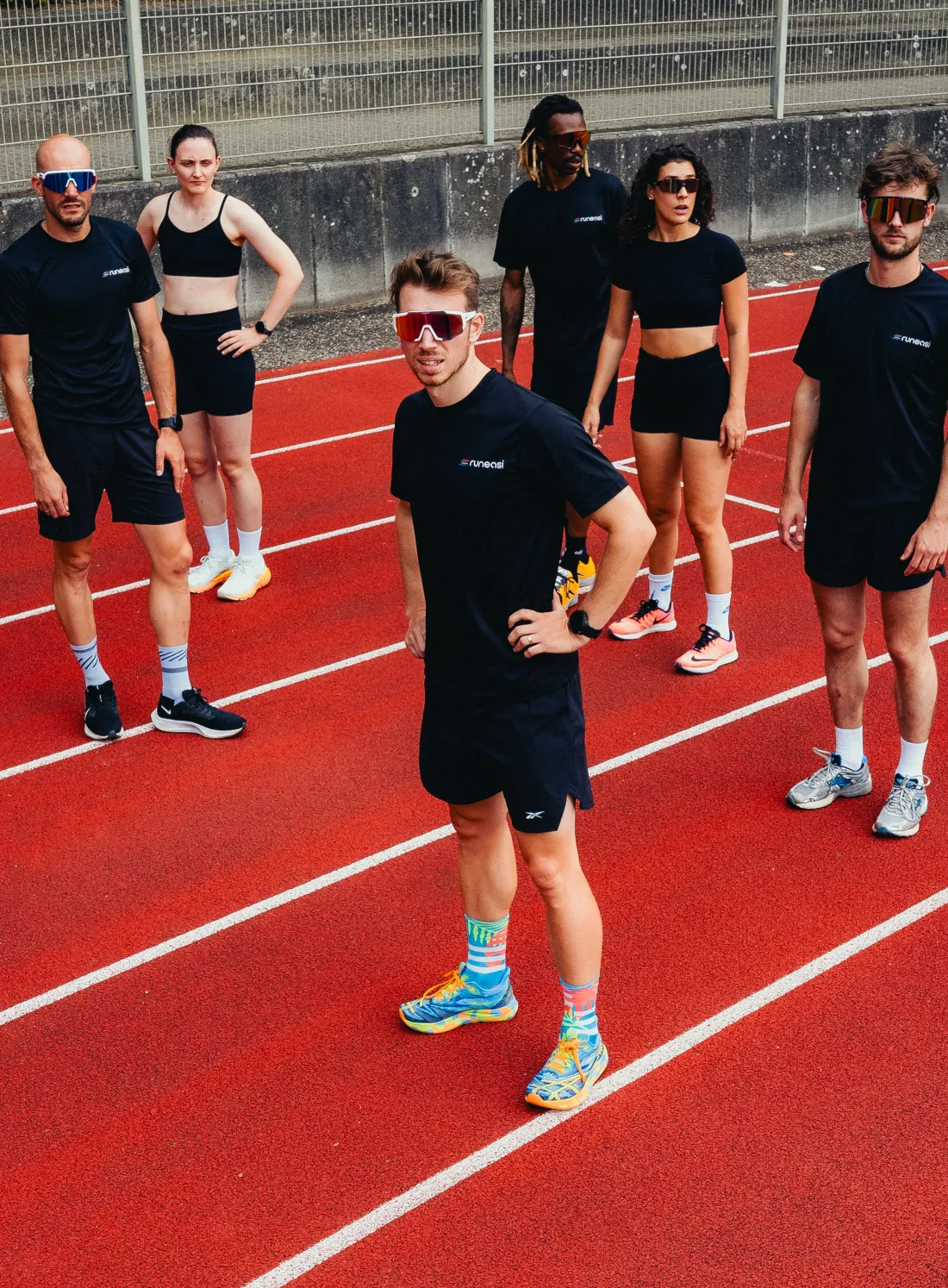 Six runners standing on a red running track