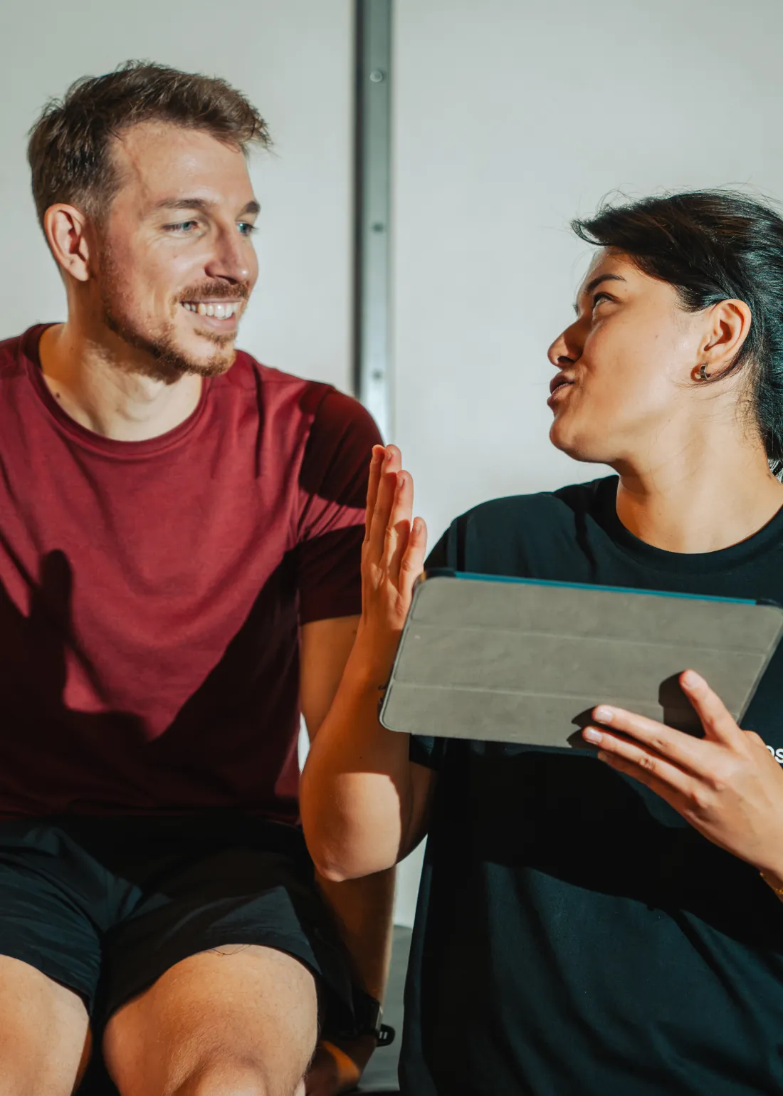 A tester with a tablet talks with a runner in a red shirt about his results