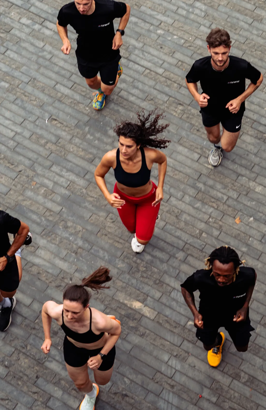 Five runners seen from above, running on paving stones