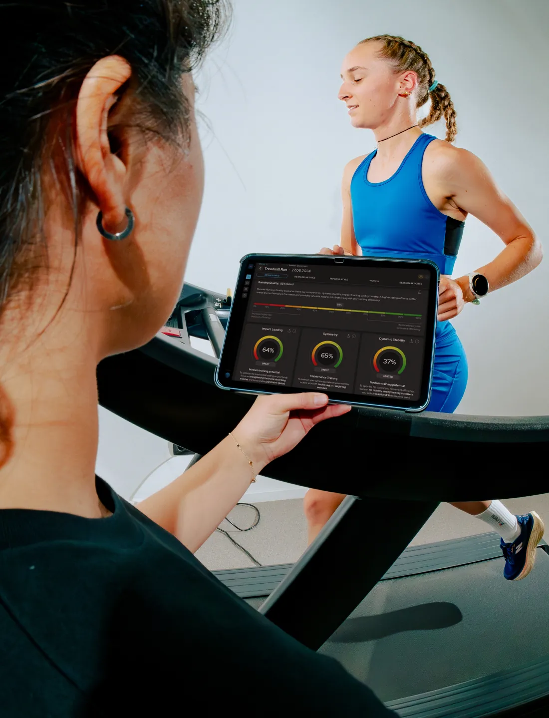 A tester holds a tablet with three Runeasi score dials while a runner runs on a treadmill