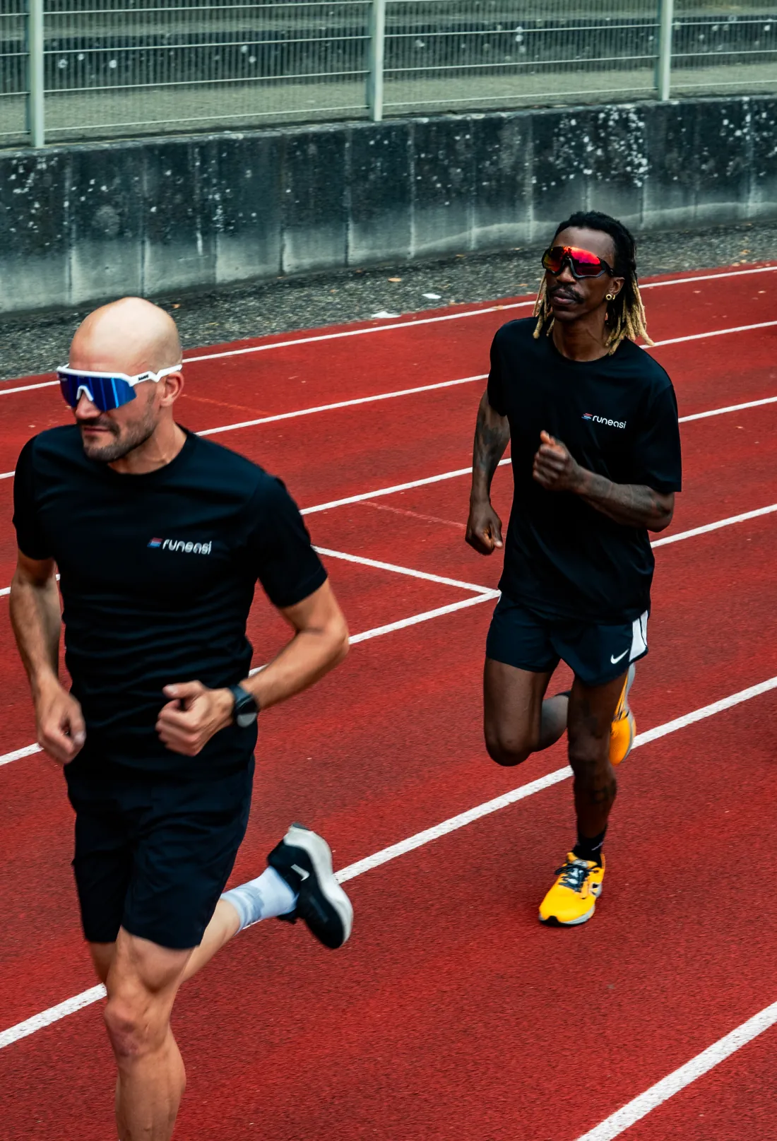 Two runners on a red running track